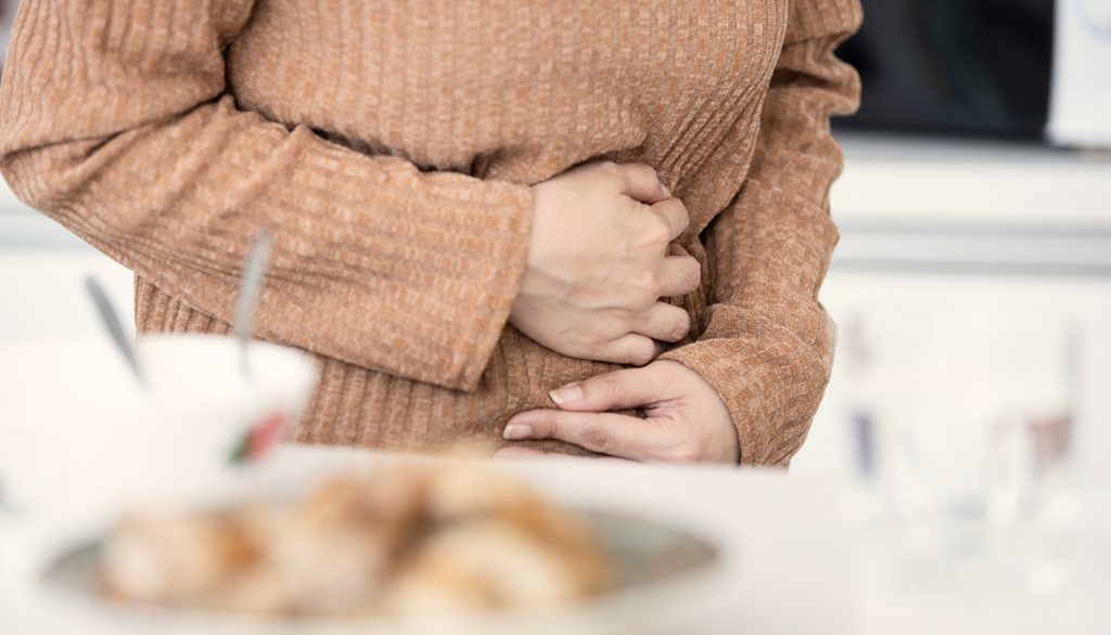 Eine Frau die ihren Bauch hält weil sie Verdauungsprobleme hat