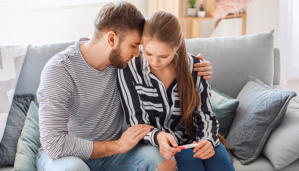 Frau und Mann mit negativem Schwangerschaftstest in der Hand