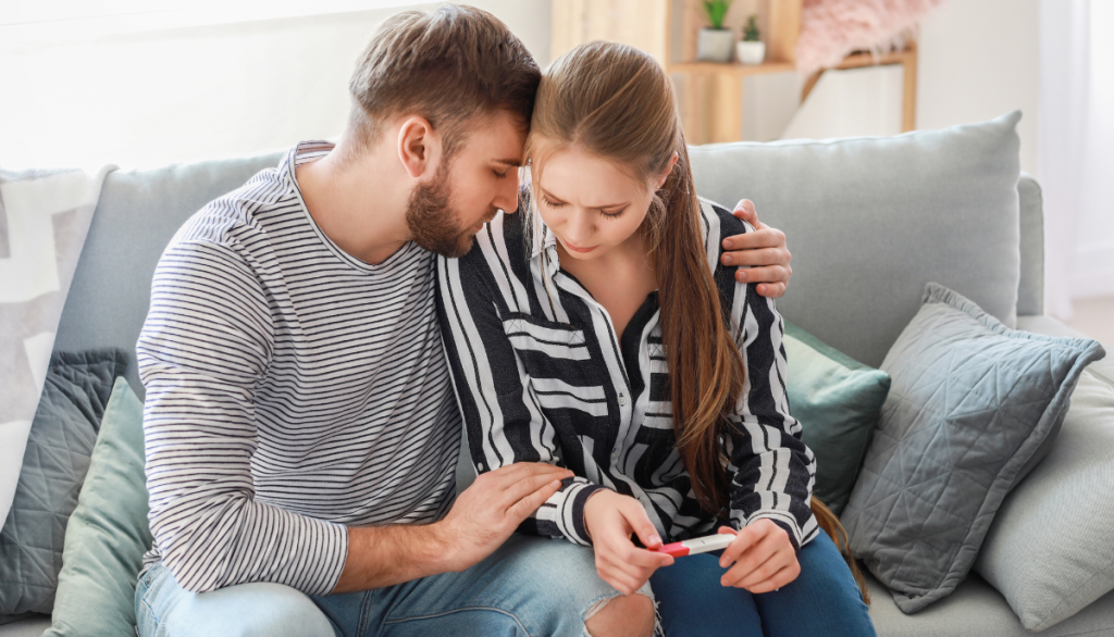 Frau und Mann mit negativem Schwangerschaftstest in der Hand