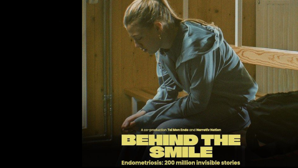 Filmszene aus dem Kurzfilm Behind the Smiles mit einer jungen Person in einem Klassenzimmer